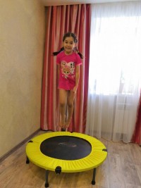  девочка прыгает на батуте дома